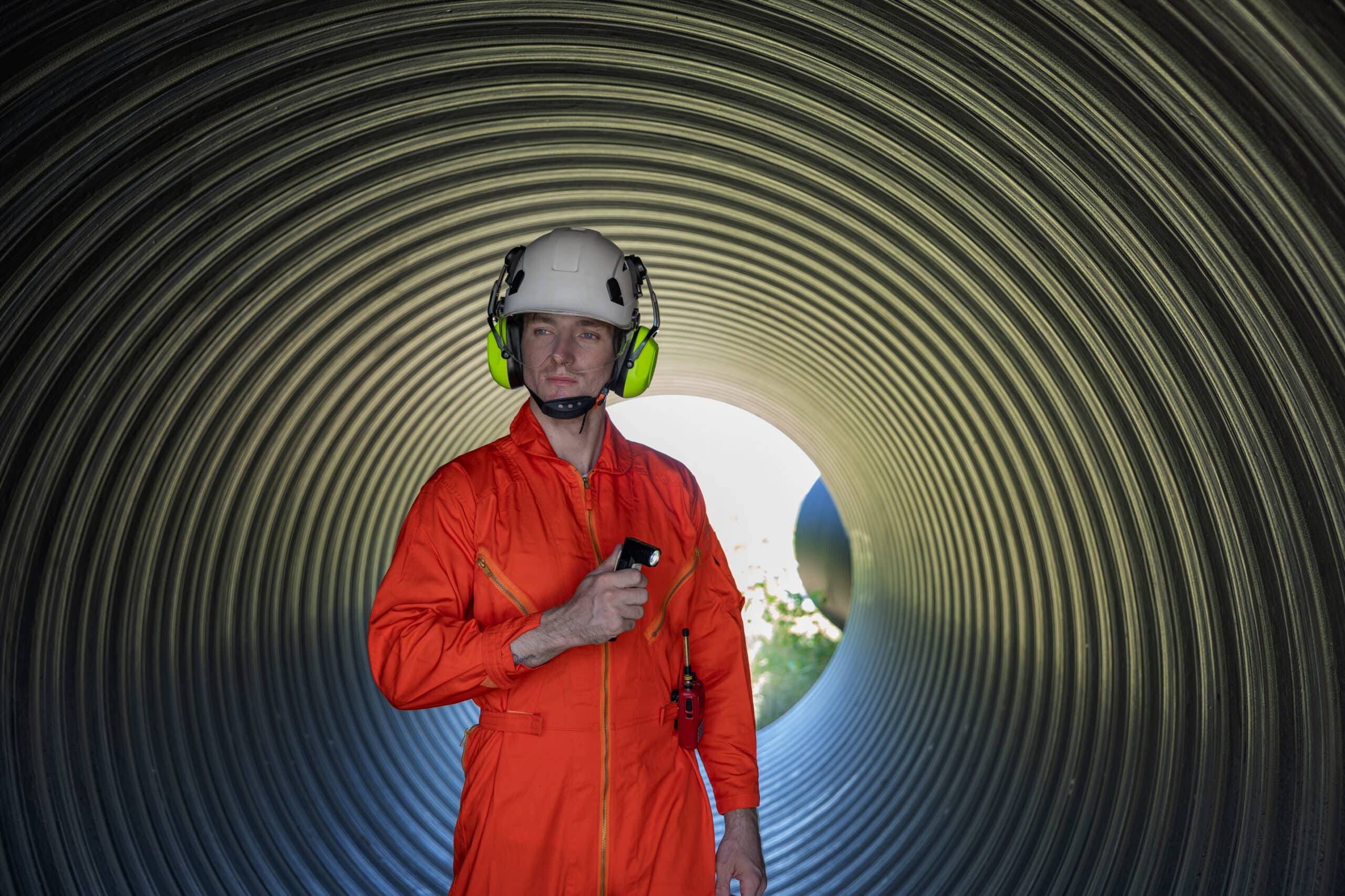 Mangatwacht met helm en gehoorbescherming inspecteert een industriële tunnel